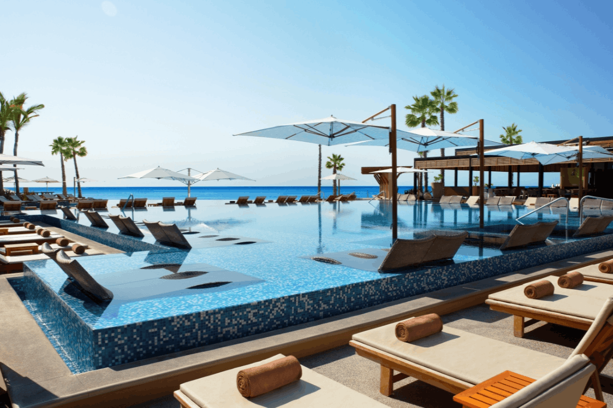 Alberca infinita de Krystal Grand Los Cabos con camastros, sombrillas y vista al mar.