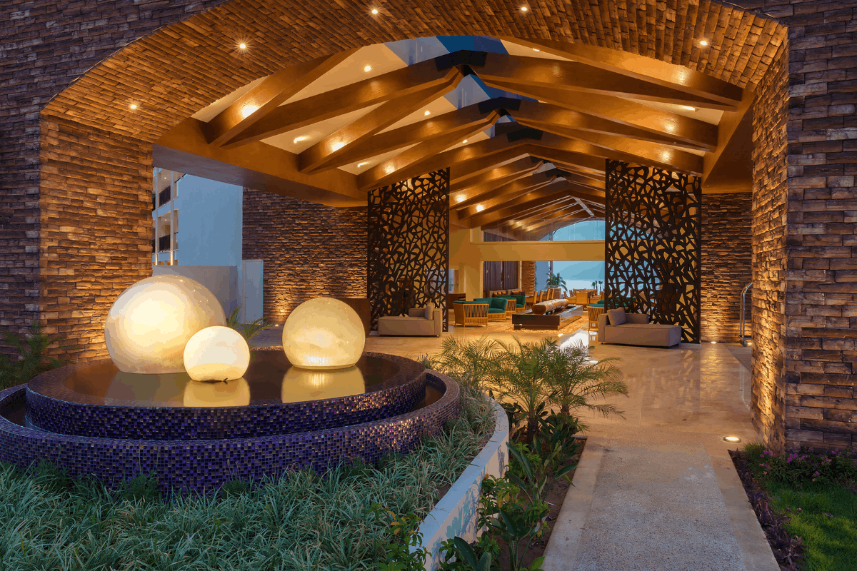 Entrada principal de Krystal Grand Los Cabos iluminada por la noche con arquitectura elegante.