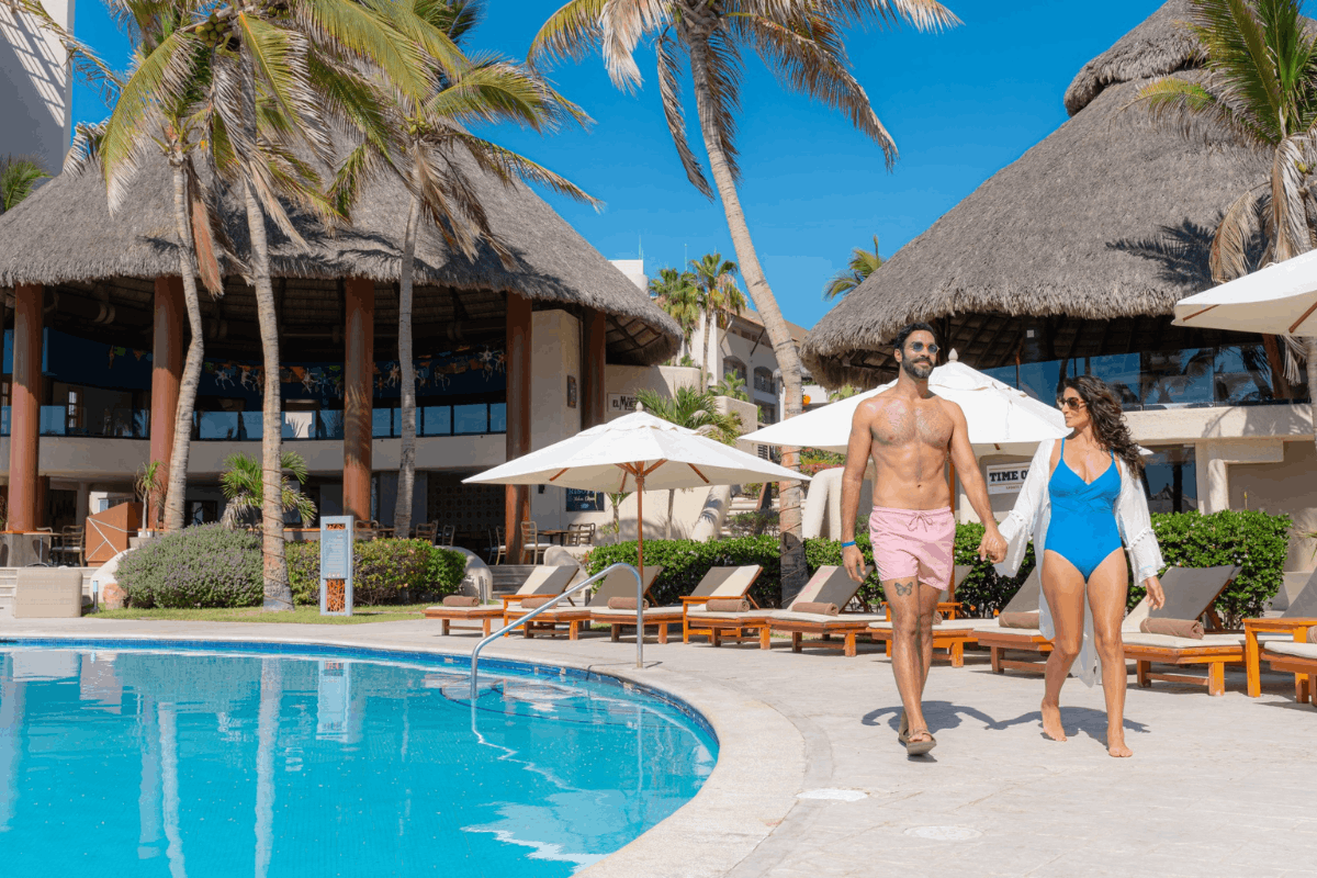 Pareja caminando junto a la alberca de Krystal Grand Los Cabos durante sus vacaciones.